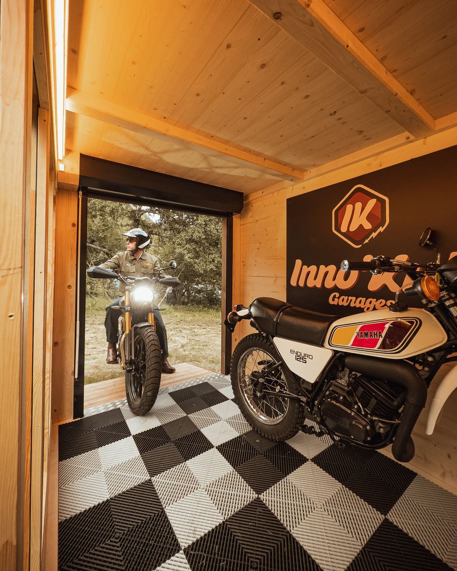 Intérieur d'un abri Inno'Kub avec une Yamaha 125 exposée et un motard rentrant sa machine