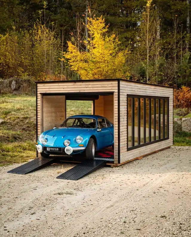 Garage en bois Inno'Kub en forêt à l'automne, Alpine A110 bleue à l'intérieur